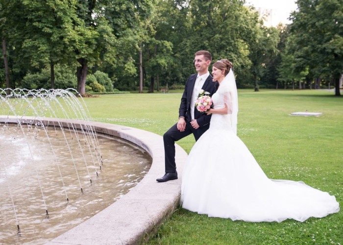 portrait von braut und bräutigam neber einem brunnen